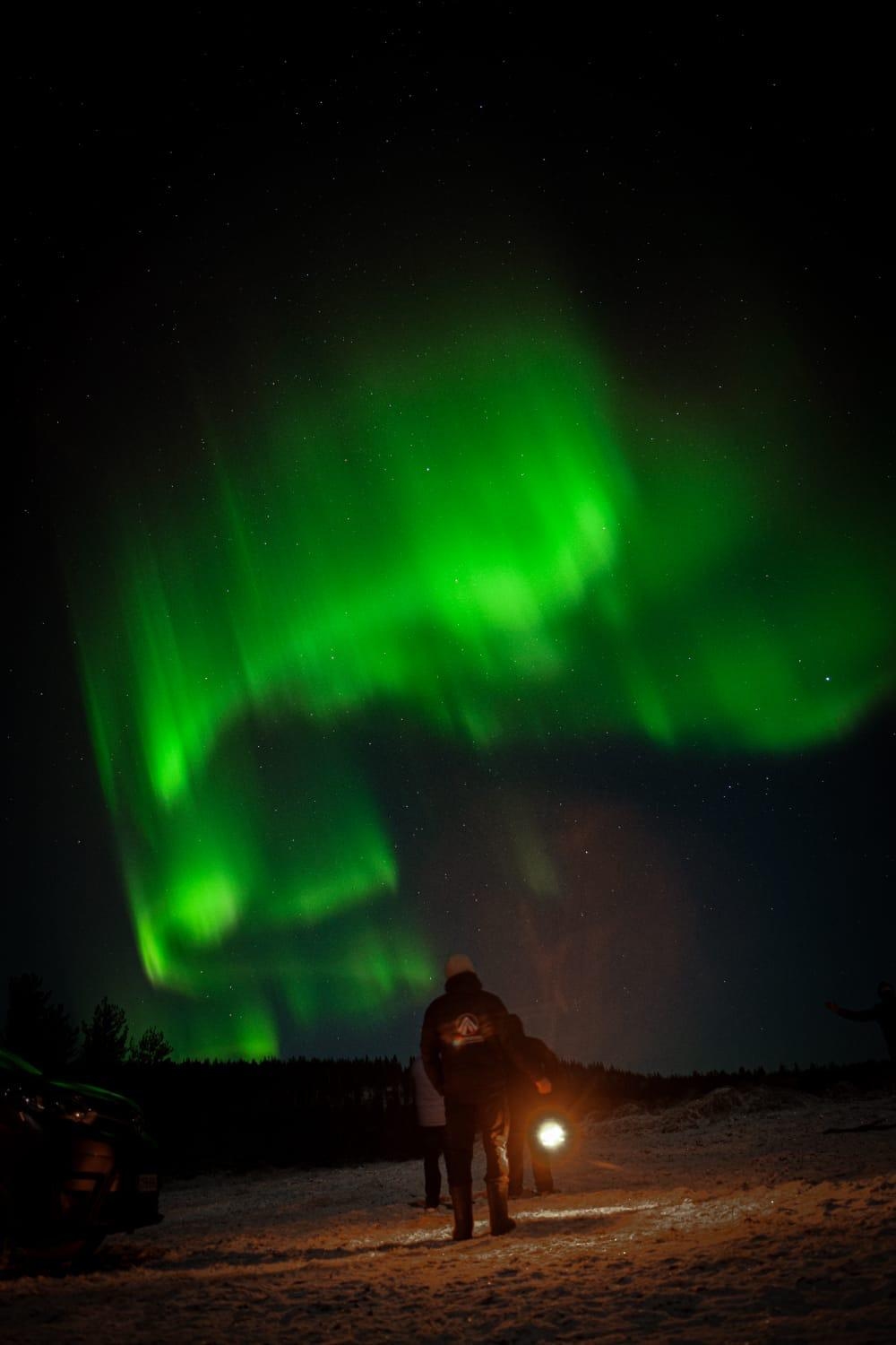A guy holding lantern under the northern lights